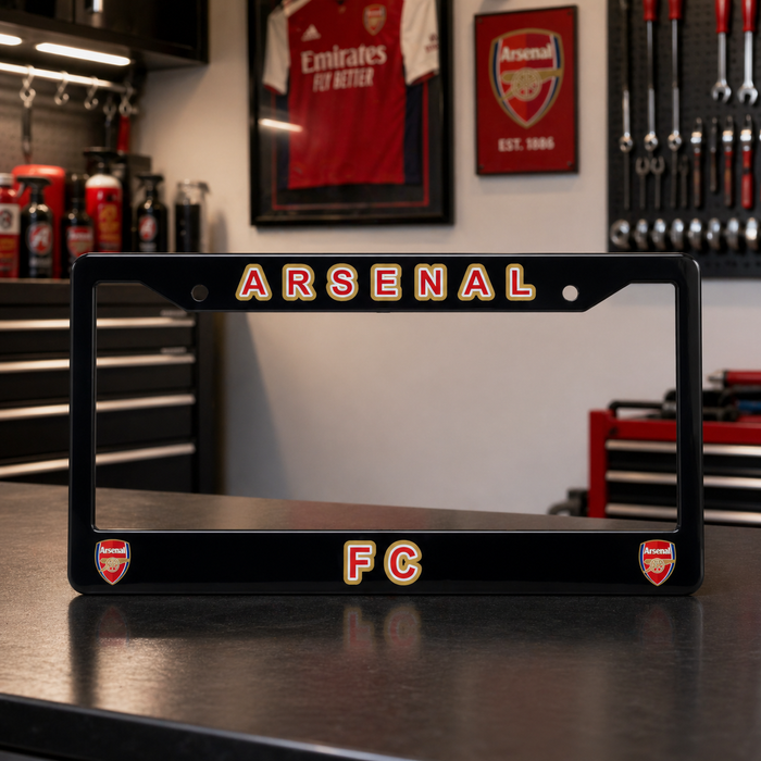 Black Arsenal FC license plate frame on a workbench with tools and sports memorabilia in the background.