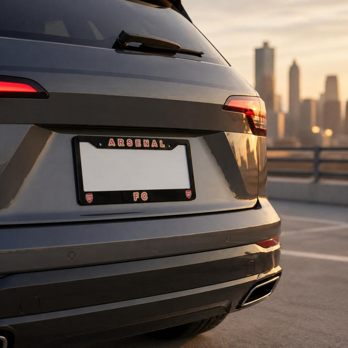 Back view of a car with 'Arsenal' license plate holder against a cityscape background