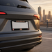 Back view of a car with 'Arsenal' license plate holder against a cityscape background