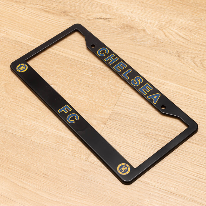 Black license plate frame with 'Chelsea FC' text on a wooden surface