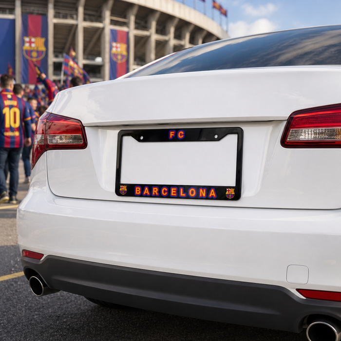 White car with a Barcelona-themed license plate in front of a stadium with fans and flags.