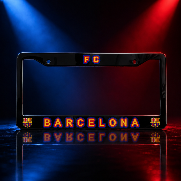 A black license plate frame featuring FC Barcelona branding, with 'FC' at the top and 'BARCELONA' in orange and blue lettering along the bottom, set against a dramatic red and blue spotlight background with a reflection below.