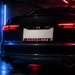 A black license plate frame mounted on the rear of a dark car, featuring the text 'FC BARCELONA' in red and orange with FC Barcelona club crests on both sides. The license plate area is blanked out in white.