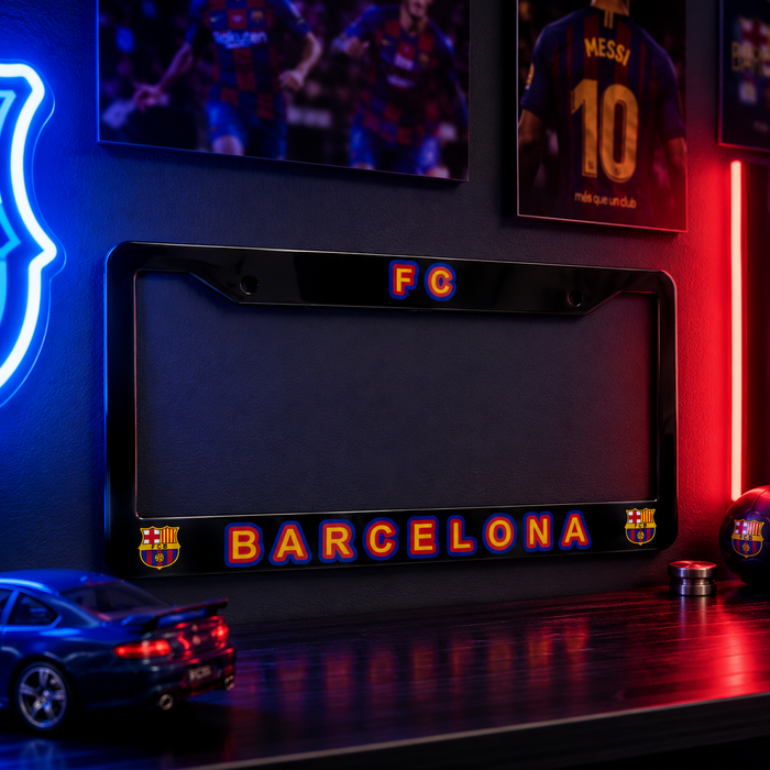A black license plate frame featuring 'FC BARCELONA' in red and blue gradient lettering, displayed on a dark shelf in a themed room with neon lights, framed jerseys, and a model car.