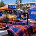A Florida Gators themed license plate frame displayed on a table at a football game. The black license plate frame features 'FLORIDA' on top and 'GATORS' on the bottom in blue with a white outline, and includes Florida Gators logos in the corners.