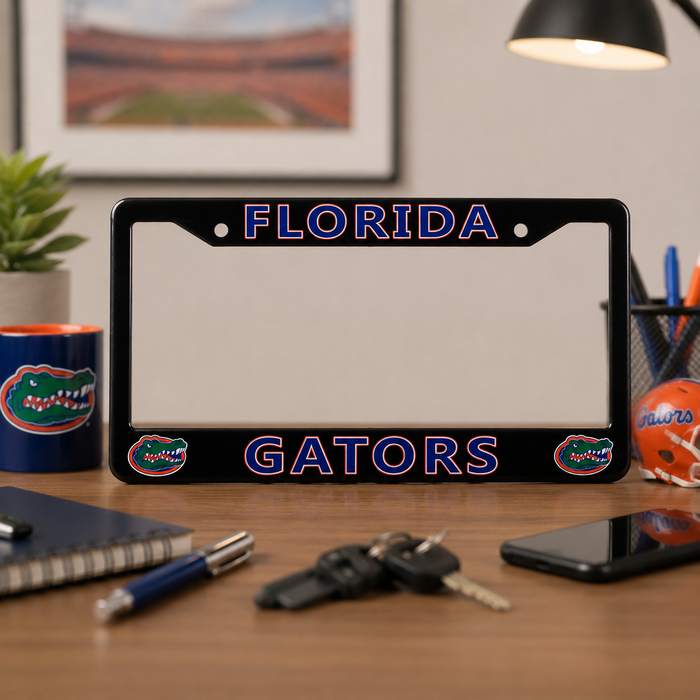 A black Florida Gators license plate frame on a wooden desk, surrounded by everyday office items like keys, a smartphone, a notebook, and a plant.