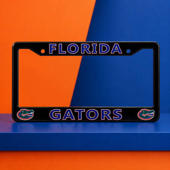 A black license plate frame featuring 'FLORIDA' at the top and 'GATORS' at the bottom in blue outlined lettering, with two Florida Gators alligator logos on the lower corners. The frame is displayed on a blue surface against a diagonally split orange and blue background.