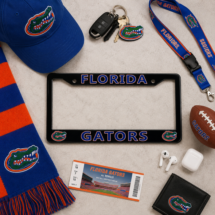 Florida Gators themed flat-lay collection featuring a black license plate frame with blue and orange lettering, a blue baseball cap, a blue and orange scarf, a lanyard, a football, earbuds, a ticket, and a wallet, all arranged on a textured light beige background.