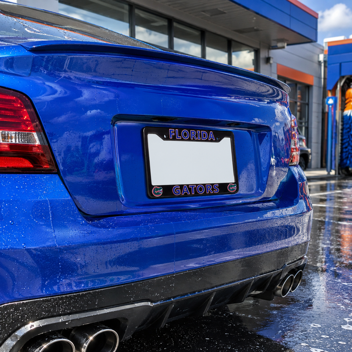 Close-up rear view of a blue car at a wet outdoor car wash, showing a black license plate frame with 'FLORIDA' at the top and 'GATORS' at the bottom in purple lettering.