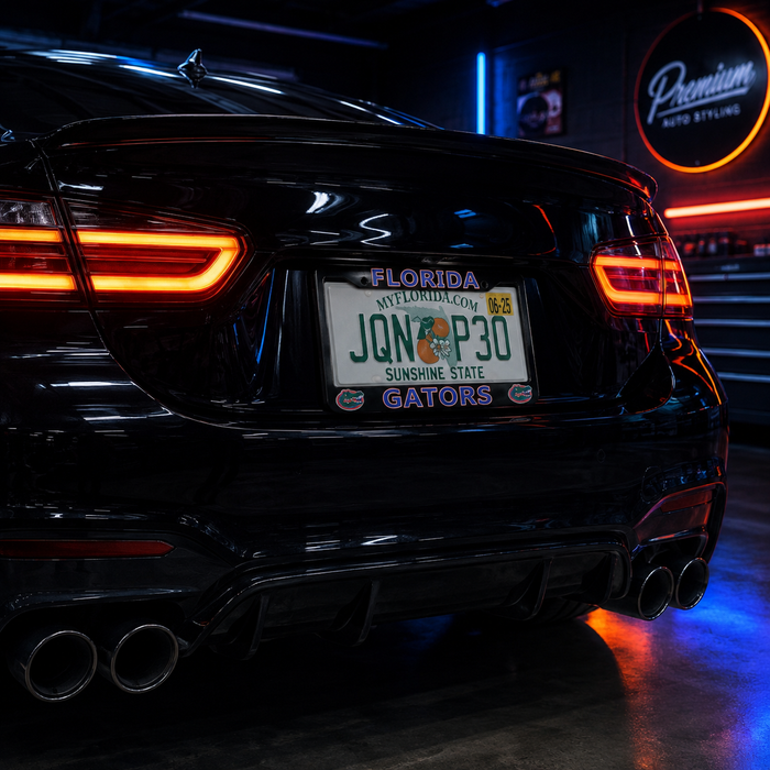 A black car rear end in a garage setting, featuring a custom Florida license plate with a Gators logo and name, dual exhaust pipes, and illuminated LED taillights.