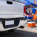 A close-up rear view of a white pickup truck at a sunny outdoor event, featuring a custom Florida Gators license plate frame with the words 'FLORIDA GATORS' in blue and orange lettering.