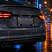A close-up rear view of a dark gray car on a wet city street at night, featuring a custom license plate frame with the word 'FLORIDA' at the top and 'GATORS' in purple with gator logo accents at the bottom.