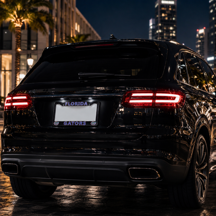 A black luxury SUV photographed from the rear at night on a wet city street, with illuminated taillights, a Florida license plate, and blurred buildings and palm trees in the background.