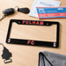 Black license plate frame with 'FULHAM FC' text on a wooden surface with car keys and documents.