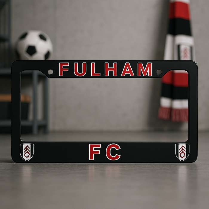 Black license plate frame with 'Fulham FC' text and logos on a gray surface.