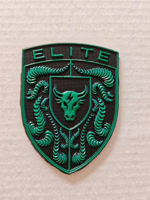 A green and black porsche emblem featuring the word 'ELITE' at the top, a bull head in the center, and crumrine designs around the border, photographed on a light textured background.