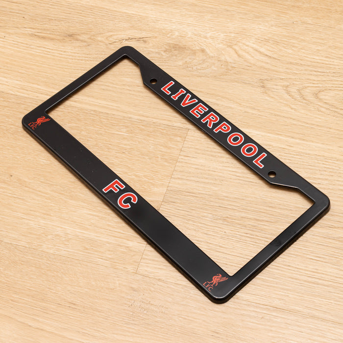 Black license plate frame with 'Liverpool FC' text on a wooden surface