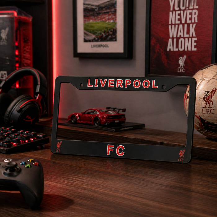Liverpool FC license plate frame on a desk with gaming accessories and sports memorabilia.