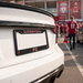 White car with Liverpool FC license plate frame at a sports event.