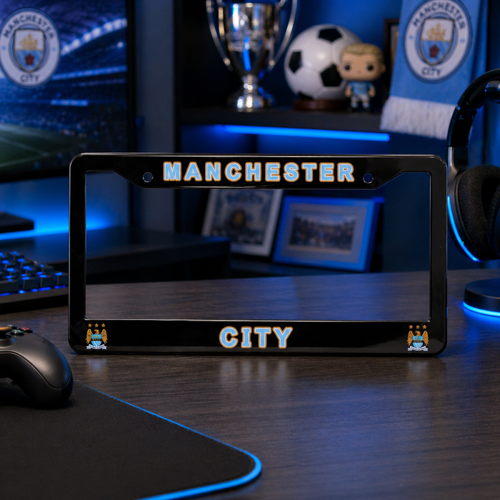 Manchester City-themed license plate frame on a desk with sports memorabilia in the background