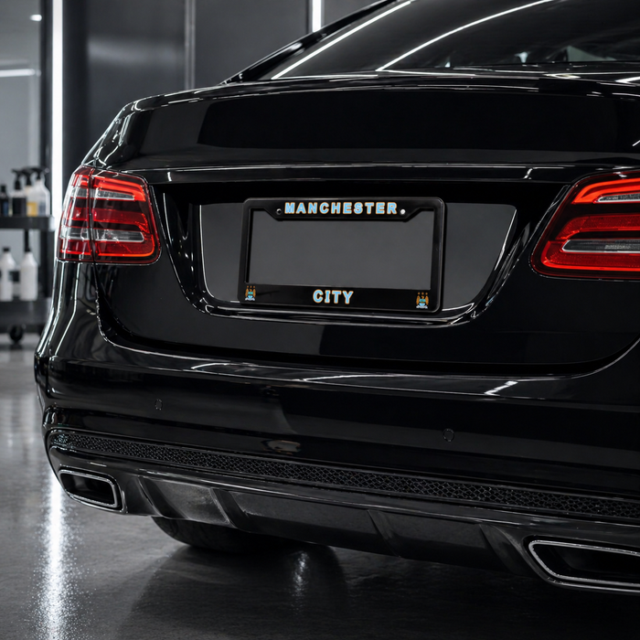 Black car with 'Manchester City' license plate in a showroom.