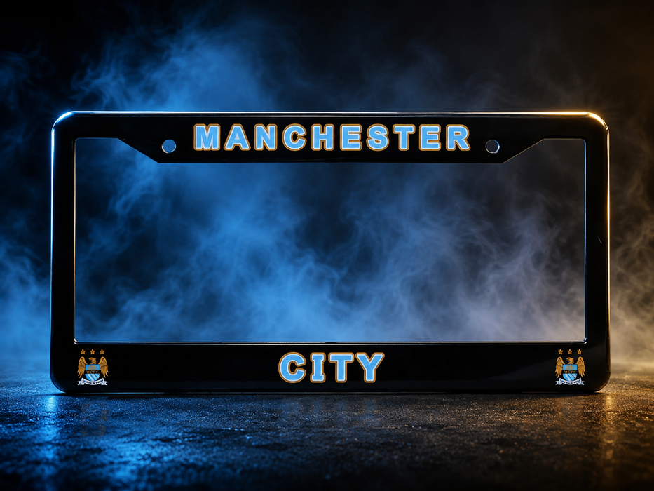 A black license plate frame featuring 'MANCHESTER' at the top and 'CITY' at the bottom, with Manchester City crest details in the corners, set against a smoky blue and black background.