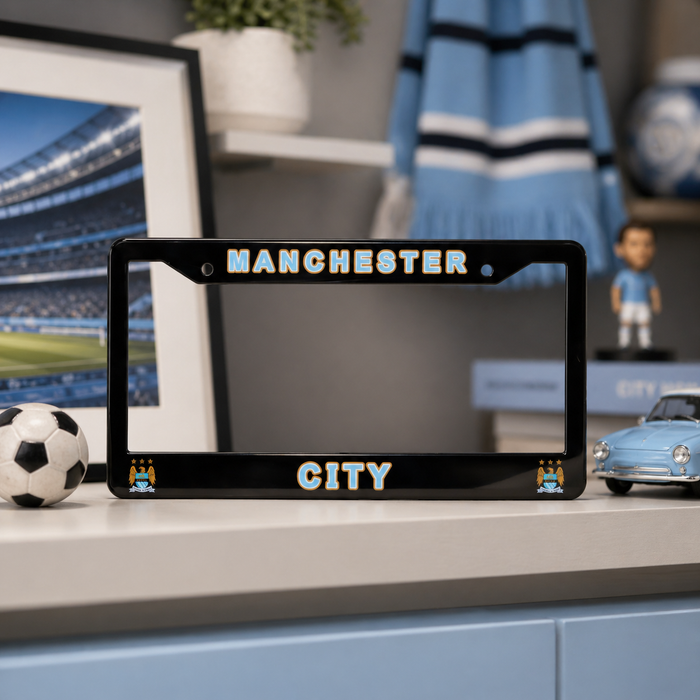 Black license plate frame with 'Manchester City' text on a shelf with sports-themed decor.