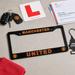 Manchester United license plate frame with car keys, L-plate, and documents on a gray surface