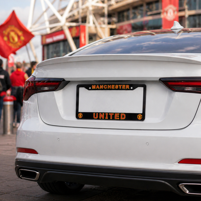 White car with Manchester United license plate in front of a stadium.
