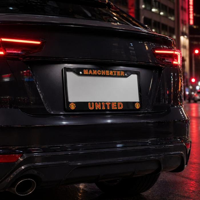 Black car with Manchester United license plate in an urban setting at night.