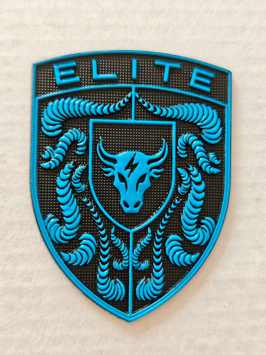 A porsche emblem with a bright blue and black design featuring the word 'ELITE' at the top, a bull head in the center, and crumrine designs around it, shown on a light textured fabric background.