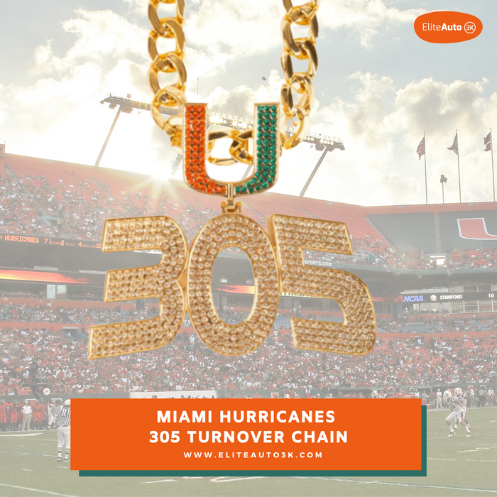 A gold chain necklace with a large '305' pendant and a 'U' charm, both encrusted with rhinestones in orange and green, set against a blurred Miami Hurricanes football stadium background. An orange banner at the bottom reads 'MIAMI HURRICANES 305 TURNOVER CHAIN' with the EliteAuto website.