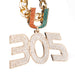 A gold-tone chain necklace featuring a large '305' pendant and a 'U' charm, both heavily embellished with clear rhinestones. The 'U' charm has one half in orange and the other in teal, while the '305' pendant is entirely clear rhinestone-covered.