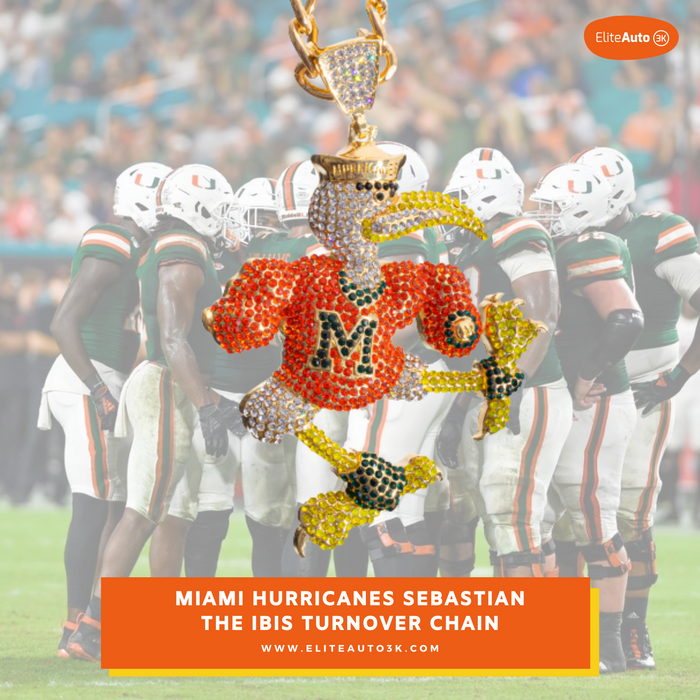 A rhinestone-embellished Miami Hurricanes football-themed pendant or charm featuring a running player in an orange jersey with 'MIA' lettering, gold accents, and a gold trophy at the top, set against a blurred Miami Hurricanes football game background. Text overlay at the bottom reads 'MIAMI HURRICANES SEBASTIAN THE IBIS TURNOVER CHAIN' with the EliteAuto brand mark in the top right.