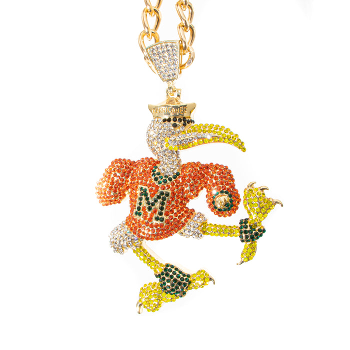 A gold-plated chain necklace with a highly detailed, rhinestone-encrusted mascot pendant. The mascot is primarily orange and yellow with green accents, wearing a gold crown and a jersey with a large letter 'M'.