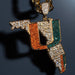 A gold-tone pendant shaped like the state of Florida, heavily embellished with rhinestones in orange, green, and clear/white tones, shown against a dark blue background.
