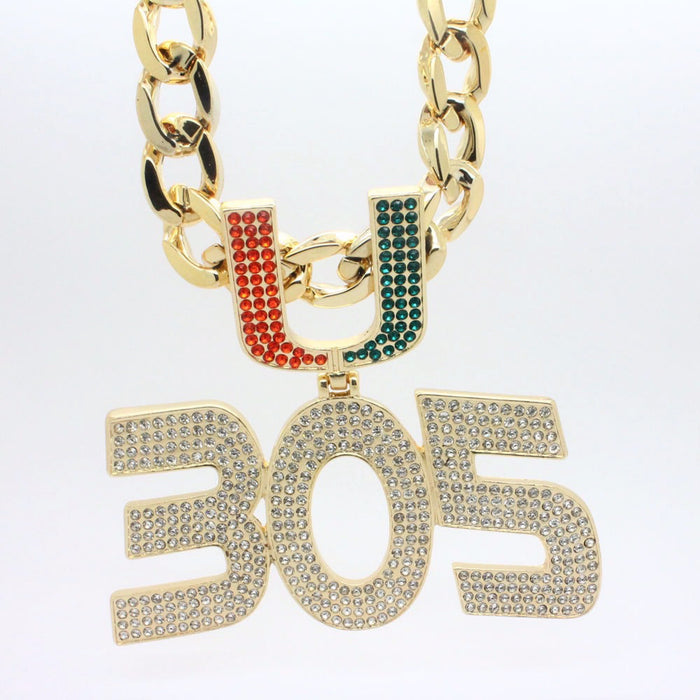 Gold-tone chain necklace with a large '305' pendant paved with clear rhinestones, and a 'U' charm split into red and green rhinestone sections, on a white background.