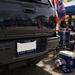 Back of a black vehicle with a Paris Saint-Germain license plate, surrounded by sports equipment and fans in the background.