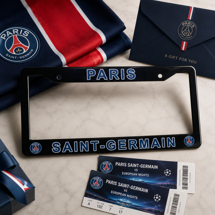 A Paris Saint-Germain license plate frame in black with blue and white lettering, displayed on a light marble surface with a folded PSG jersey, a navy gift envelope, and two match tickets.