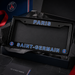 A black Paris Saint-Germain license plate frame displayed inside its branded presentation box, with 'PARIS' at the top and 'SAINT-GERMAIN' at the bottom in blue outlined lettering, plus PSG team logos in the corners.