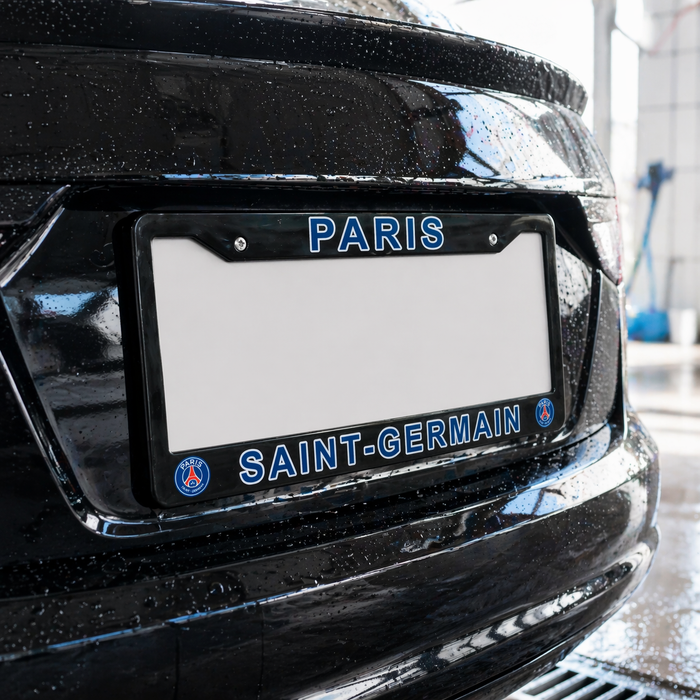 Black car with a 'Paris Saint-Germain' license plate frame on a wet surface.