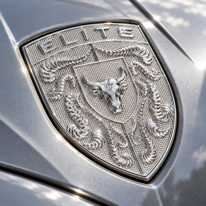 Close-up of a metallic Chrome Silver Brahma Bull Hood Emblem featuring the word 'ELITE' at the top, a bull head in the center, and crumrine designs on a textured shield, mounted on a gray vehicle surface.