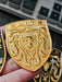 Real life image of Elite Gold Porsche Hood Emblem being held in hand.