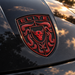 A close-up of a black car hood featuring a prominent Porsche Guards Red Brahma Bull Hood Emblem with the word 'ELITE' at the top, a bull head in the center, and crumrine details around it.