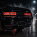 Rear view of a black muscle car on a wet night street, with illuminated red taillights and a custom license plate reading 'RAIDER NATION'.
