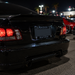 Rear view of a glossy black car at night with a custom license plate frame reading 'RAIDER NATION'.