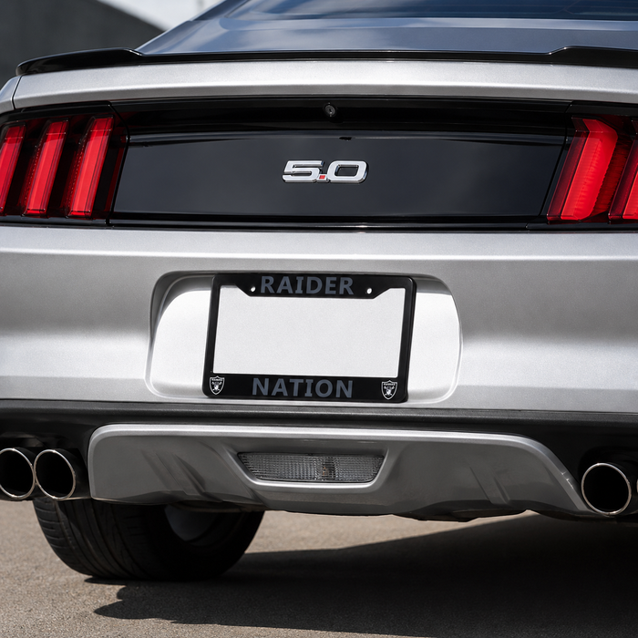 Close-up rear view of a silver Ford Mustang with a black license plate frame featuring the words 'RAIDER' at the top and 'NATION' at the bottom.