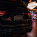 Rear view of a glossy black SUV parked on a city street at night, with the license plate frame reading "RAIDER" and "NATION" below it. The Fabulous Las Vegas sign is visible in the background.