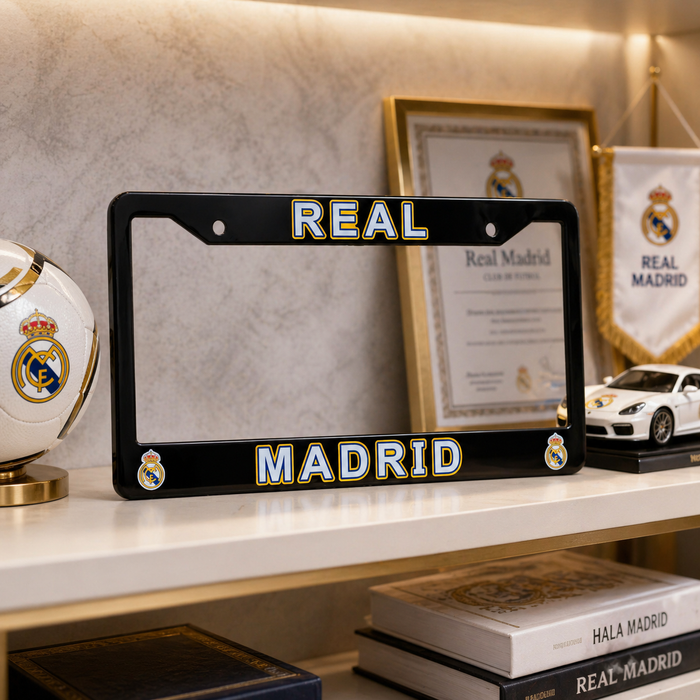 Black Real Madrid license plate frame on a shelf with sports memorabilia.