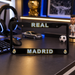 Real Madrid license plate frame on a desk with sports memorabilia in the background